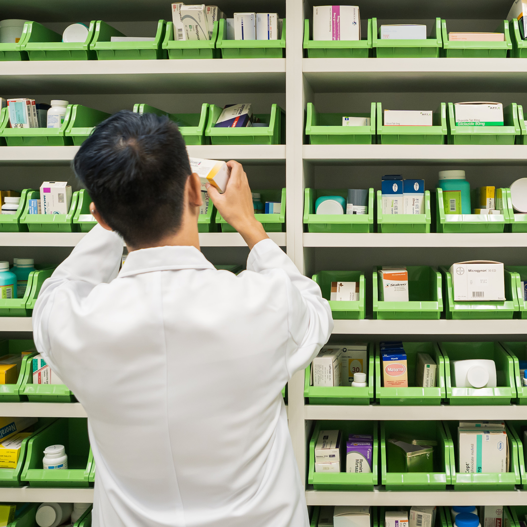 A pharmacy student in front of a dispensing cabinet.