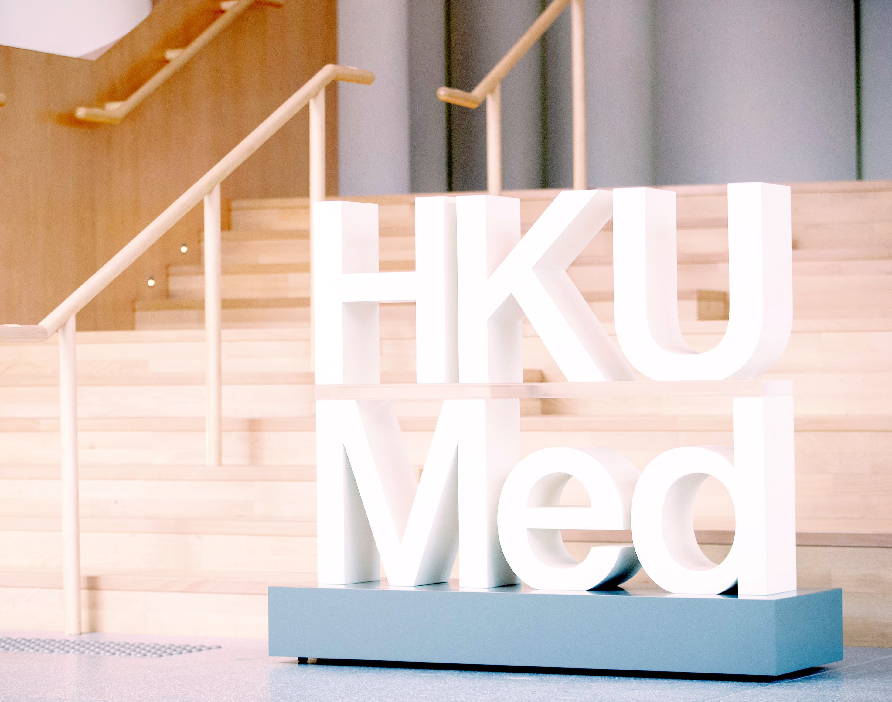 An HKUMed logo signage located in the lobby of the faculty building.