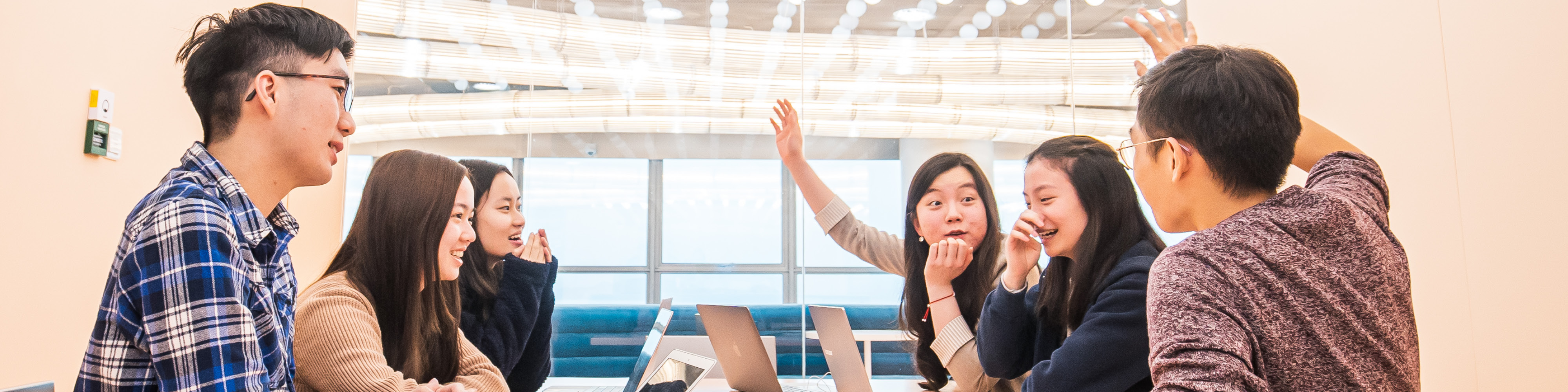 A group of students in the middle of a discussion, with two of them raising their hands.